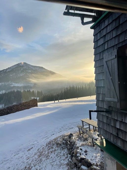 Aussicht auf die winterlichen Berge von einer Hütte im Schnee.